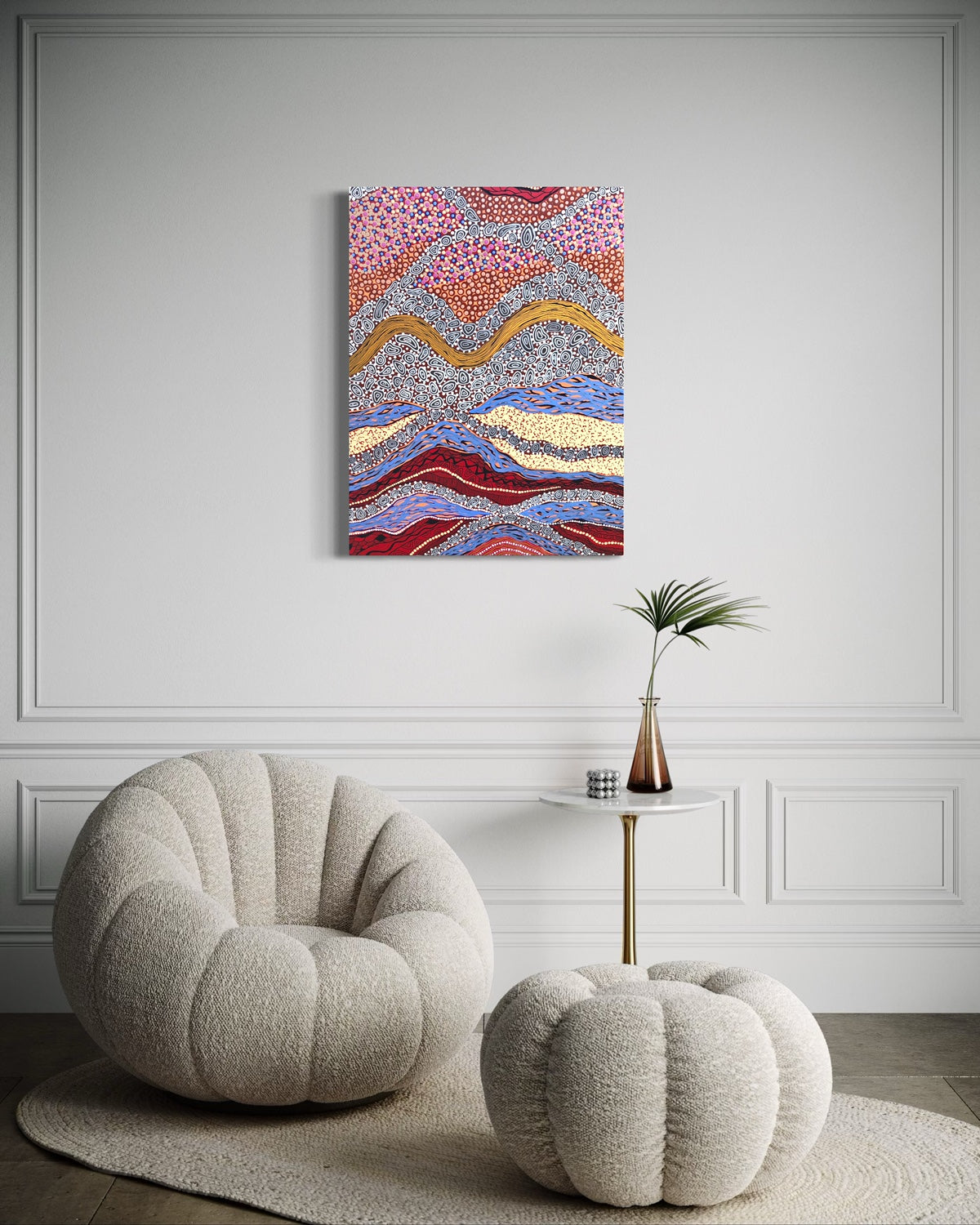 Modern interior with a textured armchair, ottoman, and abstract painting on a gray wall.