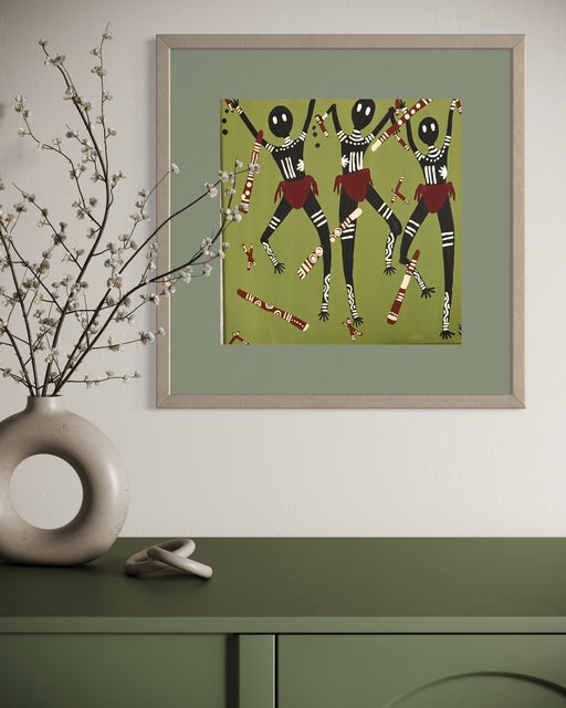 Framed artwork of three dancing figures on a green wall above a green cabinet with a vase and sculpture.